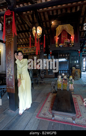 Jeune femme en costume traditionnel jaune ao dai Phung Hung vieille maison d'une visite guidée à pied visiter Hoi An Vietnam Banque D'Images