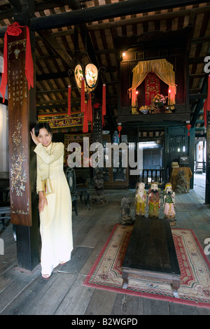 Jeune femme en costume traditionnel jaune ao dai Phung Hung vieille maison d'une visite guidée à pied visiter Hoi An Vietnam Banque D'Images