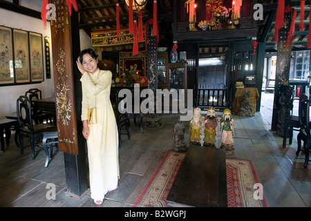 Jeune femme en costume traditionnel jaune ao dai Phung Hung vieille maison d'une visite guidée à pied visiter Hoi An Vietnam Banque D'Images