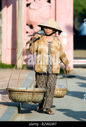 Chapeau conique femme avec du charbon dans le panier de l'épaule vue Pont couvert japonais Hoi An Vietnam Banque D'Images