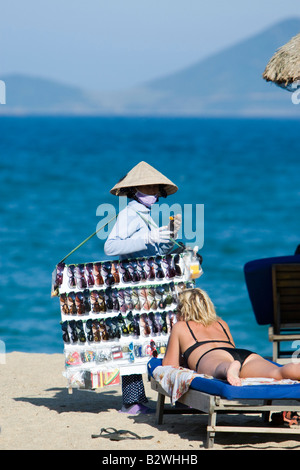 Chapeau conique femme vendant des lunettes de soleil sur la plage Nha Trang Viêt Nam resort Banque D'Images