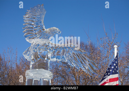 Aigle de glace avec drapeau. Une sculpture de glace de pygargue à tête blanche sur un piédestal et un drapeau américain sur le côté Banque D'Images