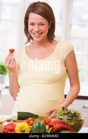 Femme enceinte en cuisine faire une salade smiling Banque D'Images