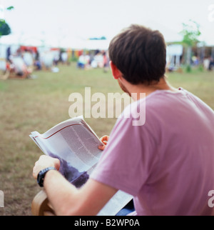 Un homme dans un T shirt rose lire un journal sur le site de l'Hay Festival Hay-on-Wye au Pays de Galles UK Banque D'Images