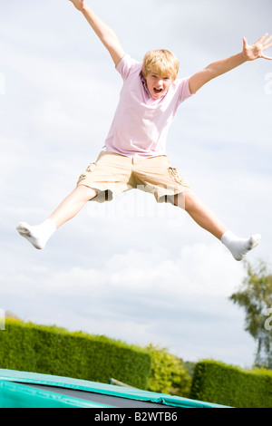 Jeune garçon sautant sur trampoline smiling Banque D'Images