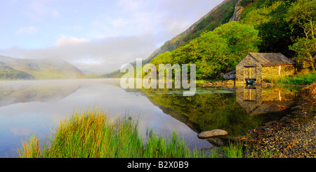 Un petit hangar à bateaux sur un beau matin brumeux et calme à Llyn Dinas dans le parc national de Snowdonia au nord du Pays de Galles Banque D'Images