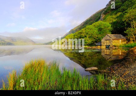 Un petit hangar à bateaux sur un beau matin brumeux et calme à Llyn Dinas dans le parc national de Snowdonia au nord du Pays de Galles Banque D'Images