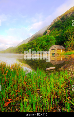 Un petit hangar à bateaux sur un beau matin brumeux et calme à Llyn Dinas dans le parc national de Snowdonia au nord du Pays de Galles Banque D'Images