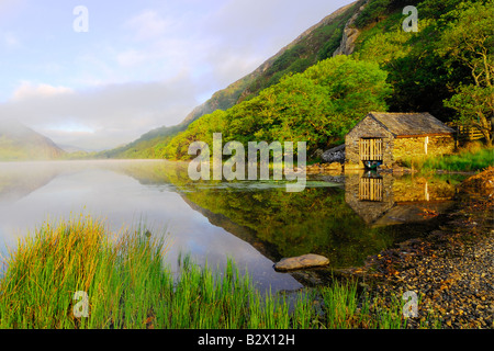 Un petit hangar à bateaux sur un beau matin brumeux et calme à Llyn Dinas dans le parc national de Snowdonia au nord du Pays de Galles Banque D'Images