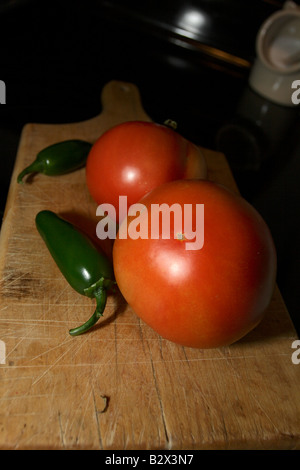 Deux tomates et piments jalapeño deux sur une planche à découper en bois. Banque D'Images
