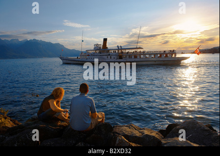 Jeune couple à la recherche d'un bateau à passagers sur le Lac Léman au coucher du soleil, Montreux, Vaud Suisse Banque D'Images