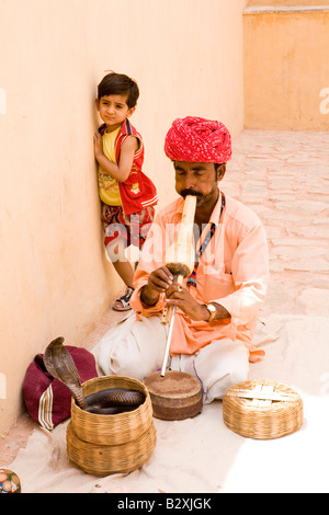 Charmeur de serpent à l'extérieur du Fort Rouge, Jaipur, Rajasthan, effectue pour les touristes et un enfant intrigué. Banque D'Images