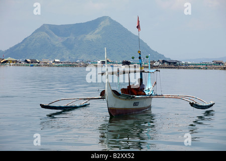 Un Philippin sur son bateau manoeuvres lac Taal en vue de l'île volcan en arrière-plan, près de Tagaytay City, Philippines. Banque D'Images