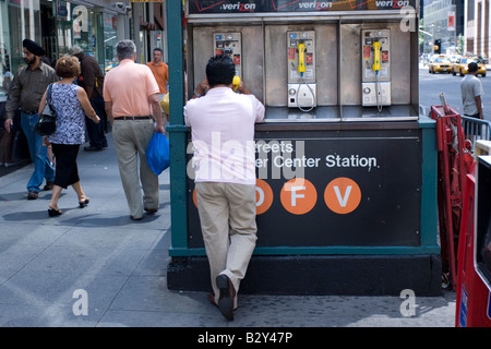 Un homme parle sur un téléphone public payant à Manhattan, NEW YORK Banque D'Images