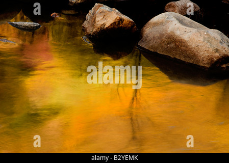 La fin de l'après-midi soleil illumine une colline au-dessus de la rivière Merced causant des réflexions dans son eau trouble Banque D'Images