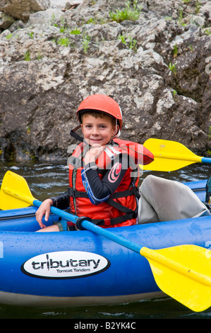 New York, au confluent de la rivière Salmon. Un enfant heureux paddles un kayak gonflable sur la rivière. Banque D'Images