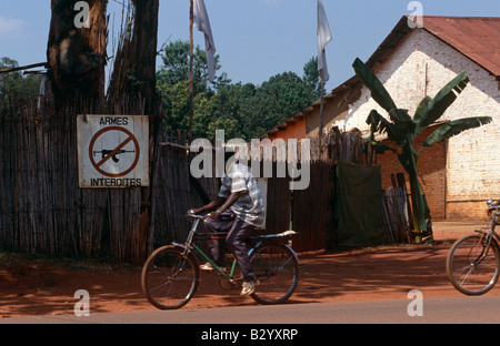 Un cycliste rides passé un panneau interdisant l'feu au Burundi. Banque D'Images