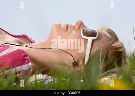 Femme couchée dans un pré, écouter de la musique Banque D'Images