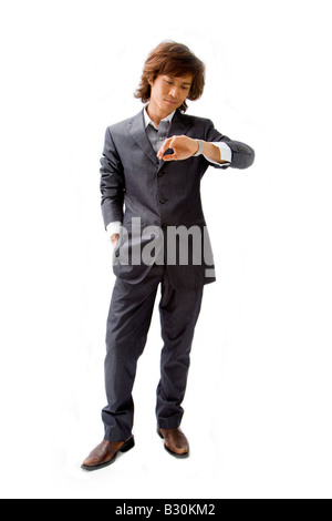 Young Asian Business homme habillé en costume gris pinstripe avec main dans poche et regardant sa montre isolated Banque D'Images