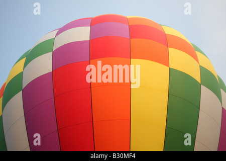 Aux couleurs vives, d'un ballon à air chaud flotte dans le ciel en début de matinée, la lumière. Banque D'Images