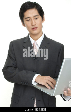 Un homme d'affaires asiatique utilise un ordinateur portable en déplacement Banque D'Images