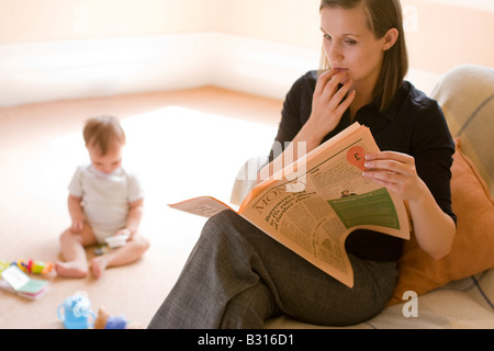 Mère regardant nouvelles financières inquiétantes dans le papier à l'enfant dans l'arrière-plan Banque D'Images