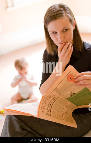 Mère regardant nouvelles financières inquiétantes dans le papier à l'enfant dans l'arrière-plan Banque D'Images