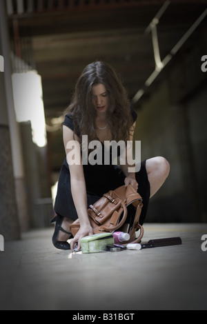 Jeune femme ramasser des objets personnels renversé sur le plancher Banque D'Images