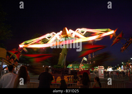 Chairoplane flying tourbillon fête foraine ride. Masse de déménagement whorling horizontale de couleur au sol avec quelques lumières de juste à l'arrière Banque D'Images