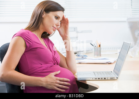 Femme enceinte au travail avec ordinateur portable à souligné Banque D'Images