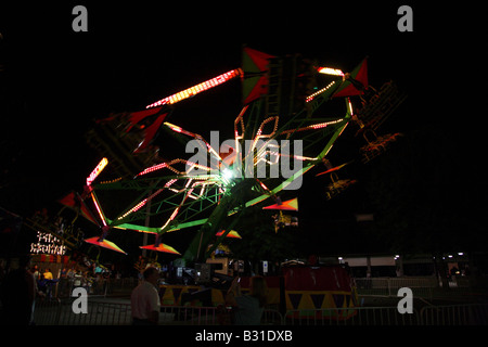 Chairoplane flying tourbillon. Jusqu'à un angle de 45 degrés. Des bandes d'éclairage avec d'autres personnes bloquées par les cerfs-volants au-dessus des cavaliers. Banque D'Images