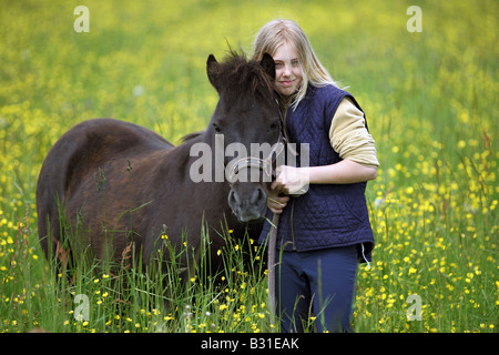 Jeune fille avec un poney sur un pré Banque D'Images