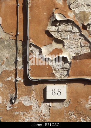 L'écaillement de peinture orange sur l'ancienne propriété mur dans Street Banque D'Images