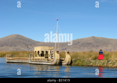 Une femmes Uros près d'un bateau de roseau sur l'auto-fashioned reed flottant îles dans le lac Titicaca, Pérou Banque D'Images