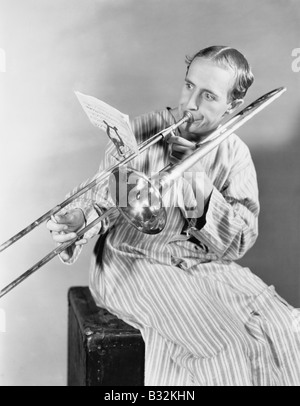 Man playing trombone en robe de nuit Banque D'Images