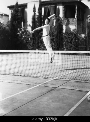 Joueur de tennis masculin saut pour shot Banque D'Images