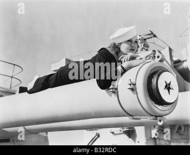 Femme dans un uniforme de marins allongé sur un cannon Banque D'Images