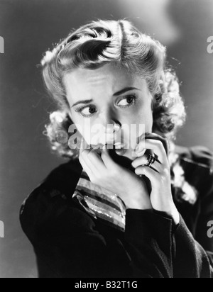 Portrait of a young woman biting son clou et à la peur Banque D'Images