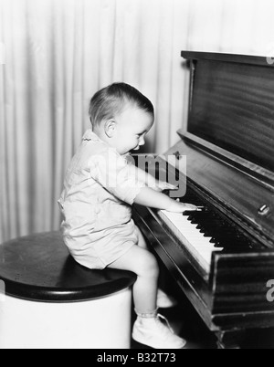 Profil d'un petit garçon assis sur un tabouret et le piano Banque D'Images