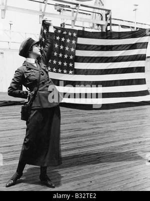 Jeune femme en uniforme militaire holding up drapeau Américain Banque D'Images