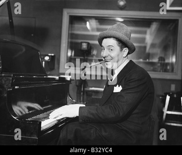 Homme avec un grand sourire et un cigare dans sa bouche jouer du piano Banque D'Images