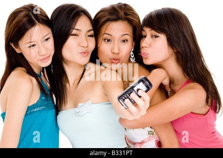 Quatre jeunes femmes attrayantes pucker-jusqu'à l'appareil photo sur le téléphone Banque D'Images