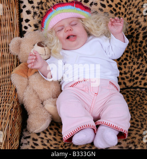 Enfant béant avec une perruque et un ours en peluche Banque D'Images