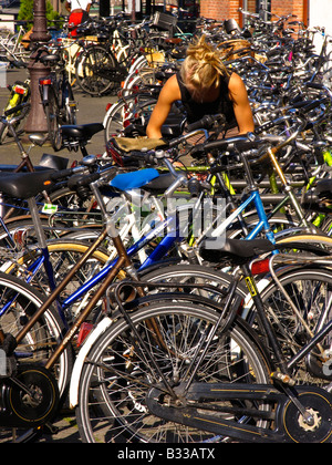 Jeune femme à une rangée de vélos hollandais à Amsterdam Banque D'Images