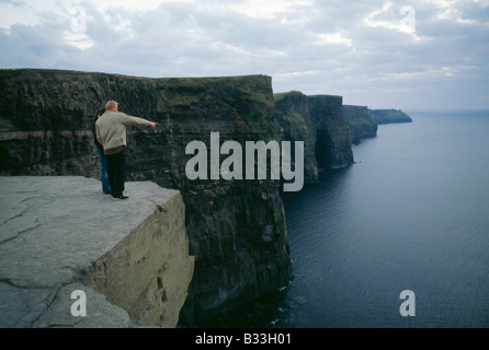 Un couple prend dans la vue depuis les falaises de Moher sur la côte irlandaise. Banque D'Images