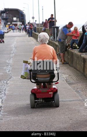 Vue arrière de la vieille dame à l'aide du fauteuil roulant motorisé électrique que les transports sur Bridlington pier. Banque D'Images
