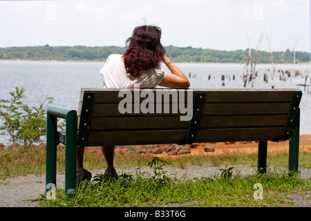 Femme sur un banc avec vue sur le lac Banque D'Images