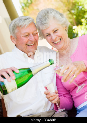 Couple on patio drinking champagne and smiling Banque D'Images