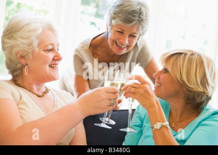 Trois femmes dans la salle de séjour toasting champagne and smiling Banque D'Images