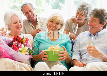 Cinq amis avec champagne et cadeaux dans la salle de séjour smiling Banque D'Images